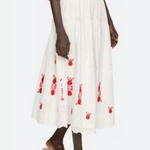 Person wearing a white dress with red floral patterns and brown sandals on a white background
