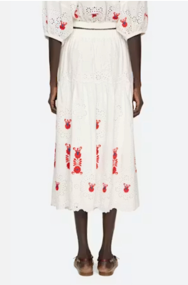 White skirt with red patterns worn by a model on a white background