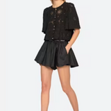 Woman wearing a black outfit with a top and shorts on a white background