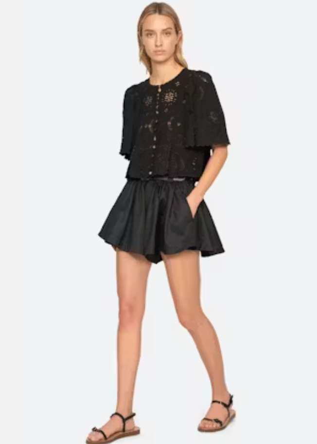 Woman wearing a black outfit with a top and shorts on a white background