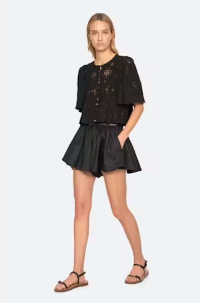 Woman wearing a black outfit with a top and shorts on a white background