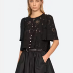 Woman wearing a black outfit with intricate designs on a white background
