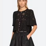 Woman wearing a black outfit with intricate designs on a white background