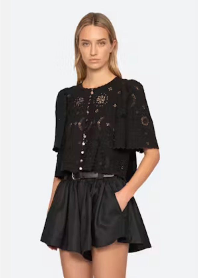 Woman wearing a black outfit with intricate designs on a white background