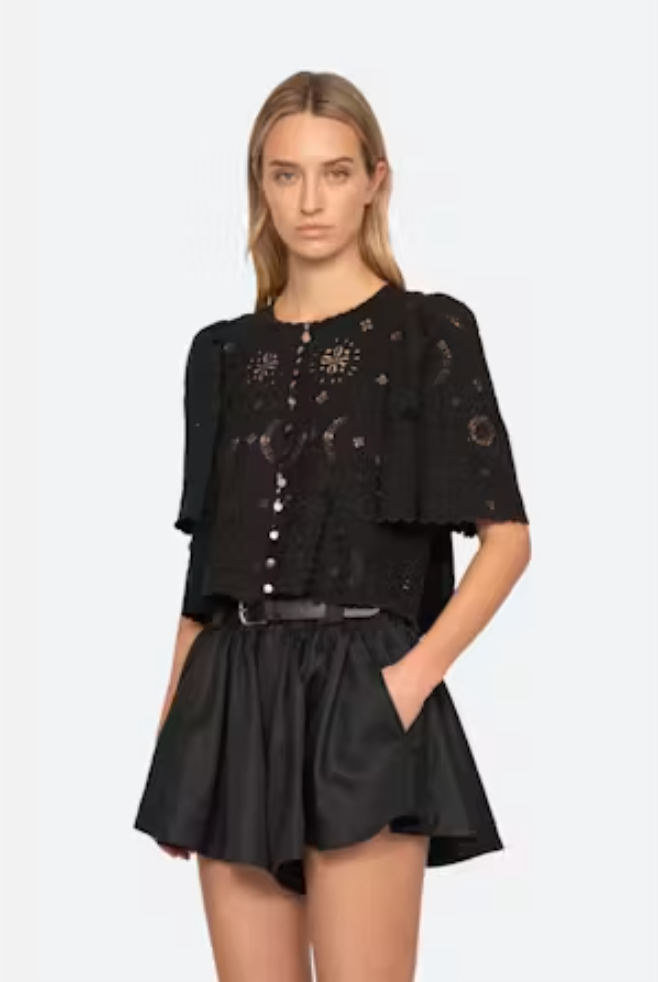 Woman wearing a black outfit with intricate designs on a white background