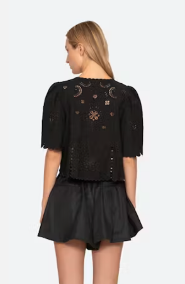 Black outfit with intricate designs on a plain background