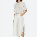 Woman wearing a white outfit with floral details on a white background