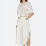 Woman wearing a white outfit with floral details on a white background
