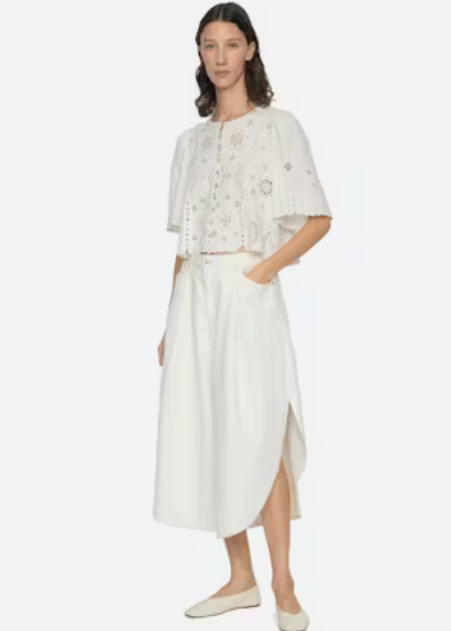 Woman wearing a white outfit with floral details on a white background