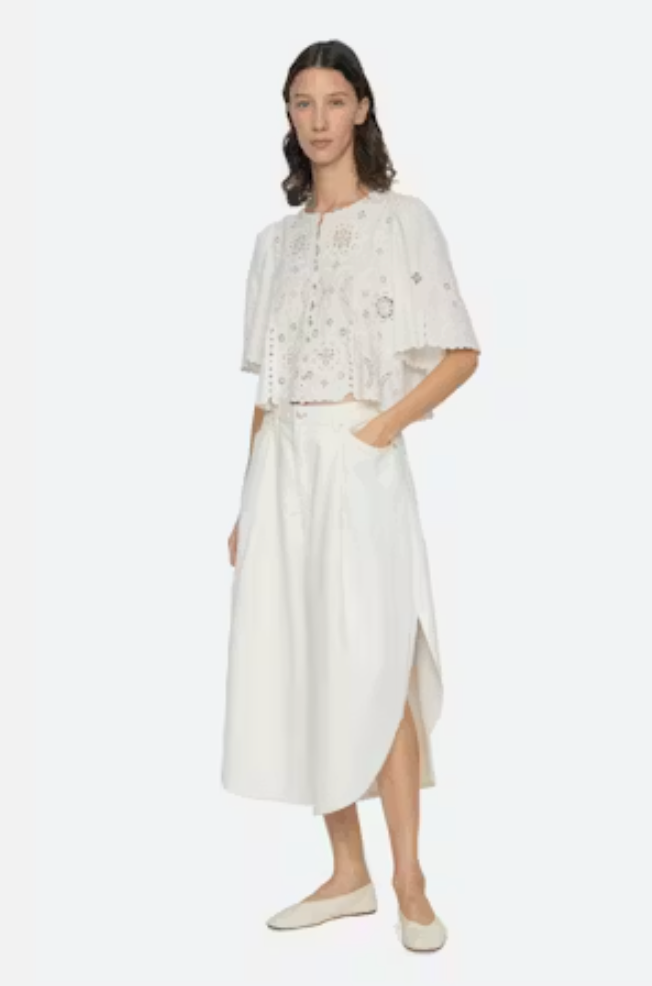 Woman wearing a white outfit with floral details on a white background