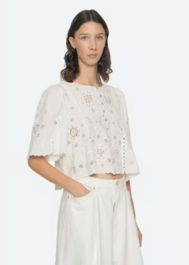 Woman wearing a white embroidered top and pants on a white background