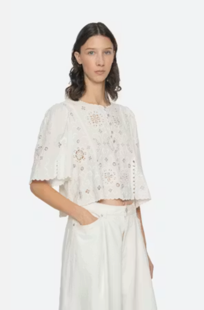 Woman wearing a white embroidered top and pants on a white background