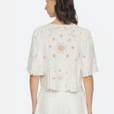Woman wearing a white embroidered top and skirt on a white background