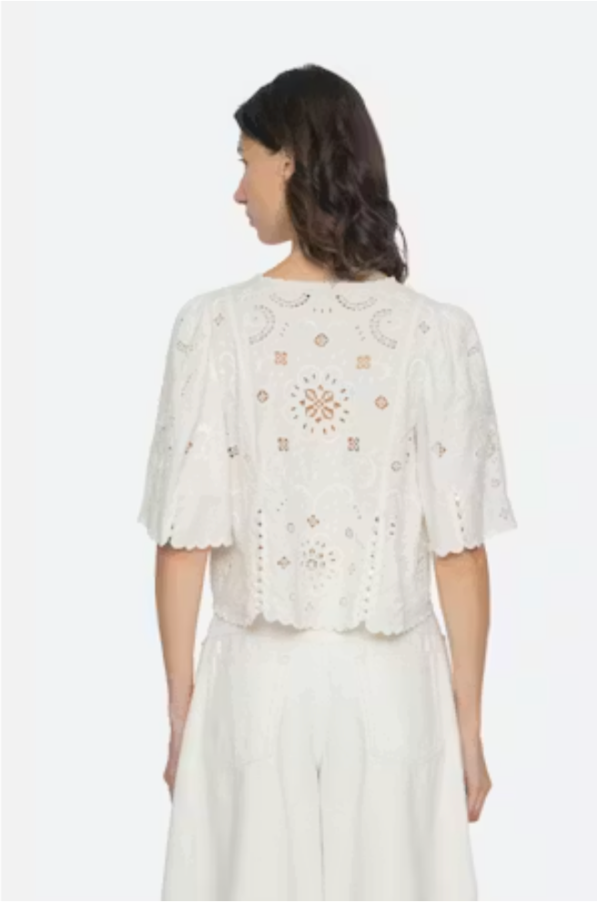 Woman wearing a white embroidered top and skirt on a white background