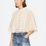 Woman wearing a white lace top and blue jeans on a white background