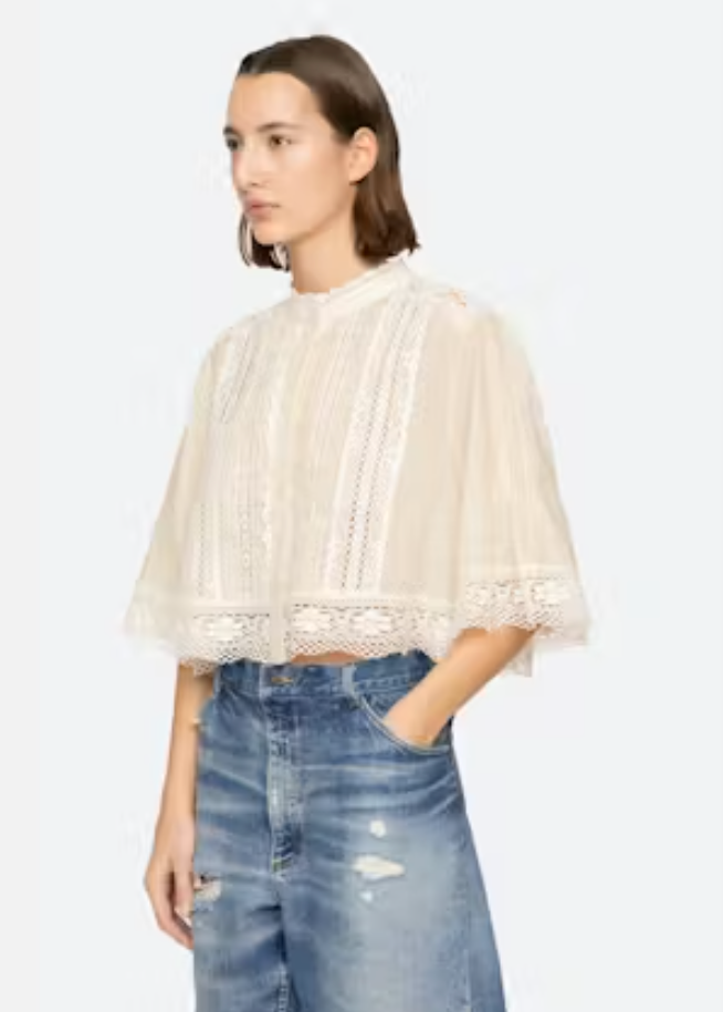 Woman wearing a white lace top and blue jeans on a white background