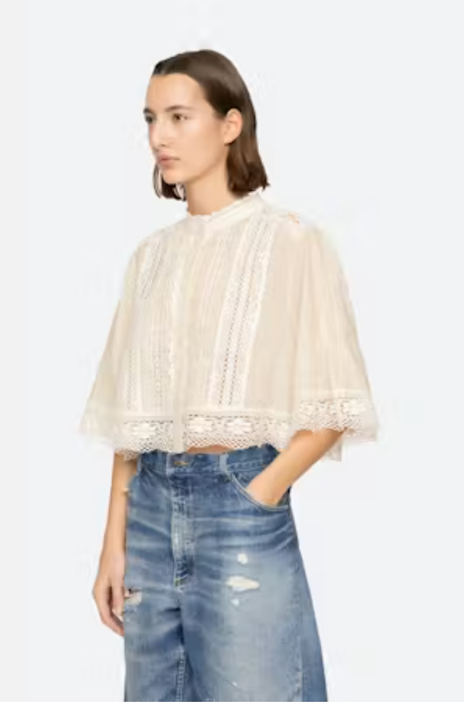 Woman wearing a white lace top and blue jeans on a white background