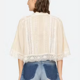 Woman wearing a beige lace top and blue jeans on a white background