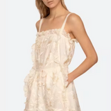 Woman wearing a white lace romper on a plain background