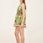 Woman wearing a green floral dress standing against a plain background