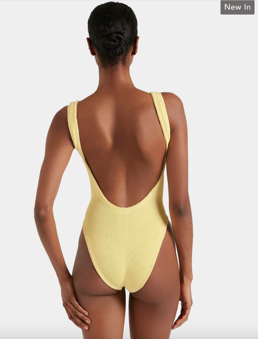 Yellow swimsuit with open back worn by a model on a white background
