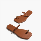 Pair of brown sandals with a gold toe ring on a white background