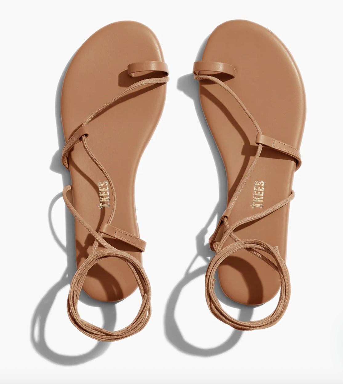 Pair of tan sandals with 'TKEES' branding on a white background
