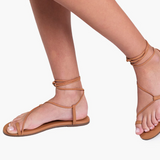 Tan sandals worn by a person on a white background
