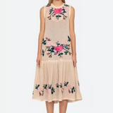 Woman wearing a beige dress with floral embroidery on a white background