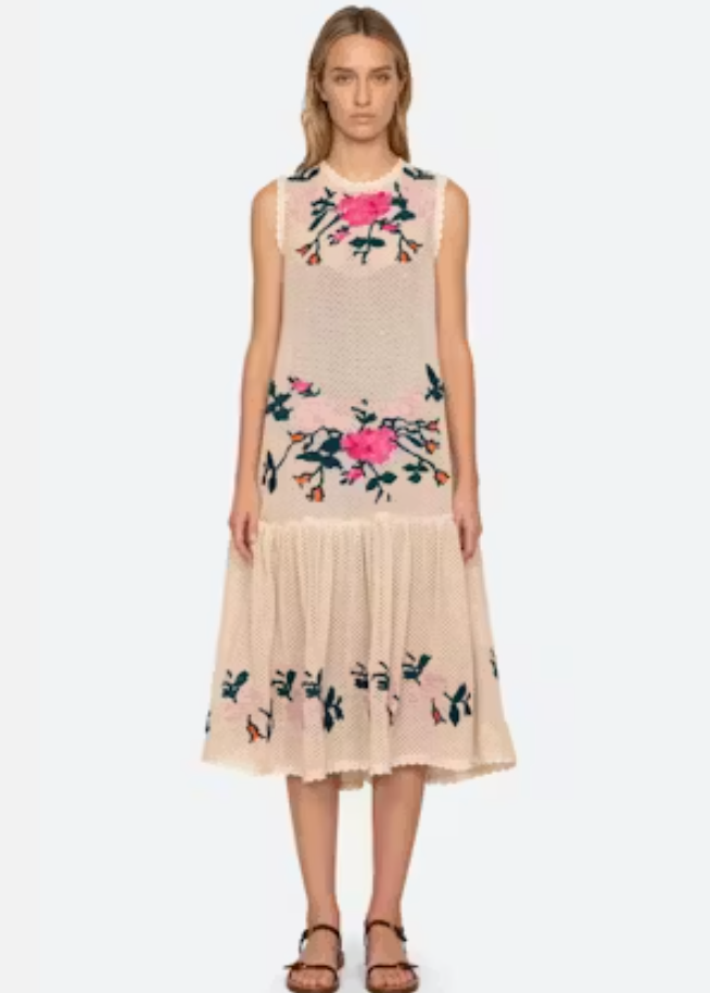 Woman wearing a beige dress with floral embroidery on a white background