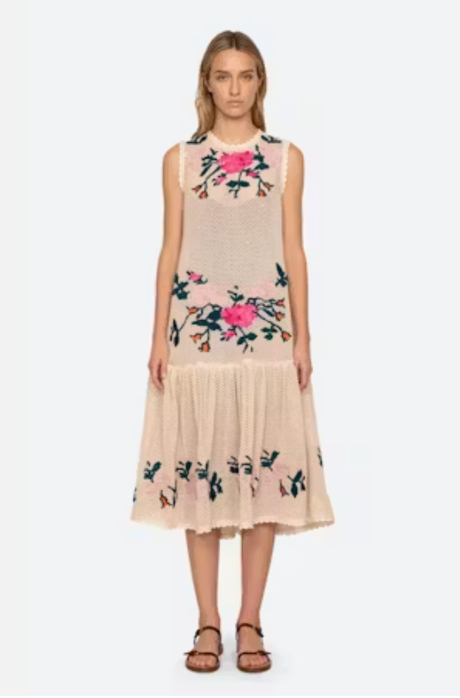 Woman wearing a beige dress with floral embroidery on a white background