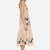 Woman wearing a beige sleeveless dress with floral patterns on a white background