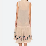 Woman wearing a beige sleeveless dress with floral embroidery on a white background