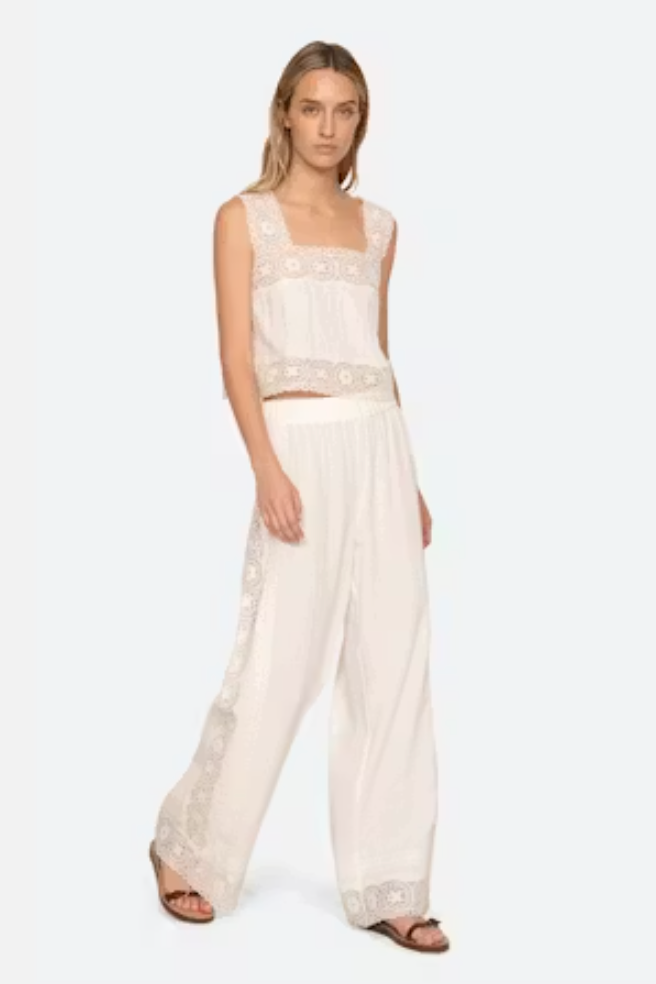 Woman wearing a white lace outfit on a plain background