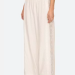 White lace-trimmed pants worn by a person on a white background