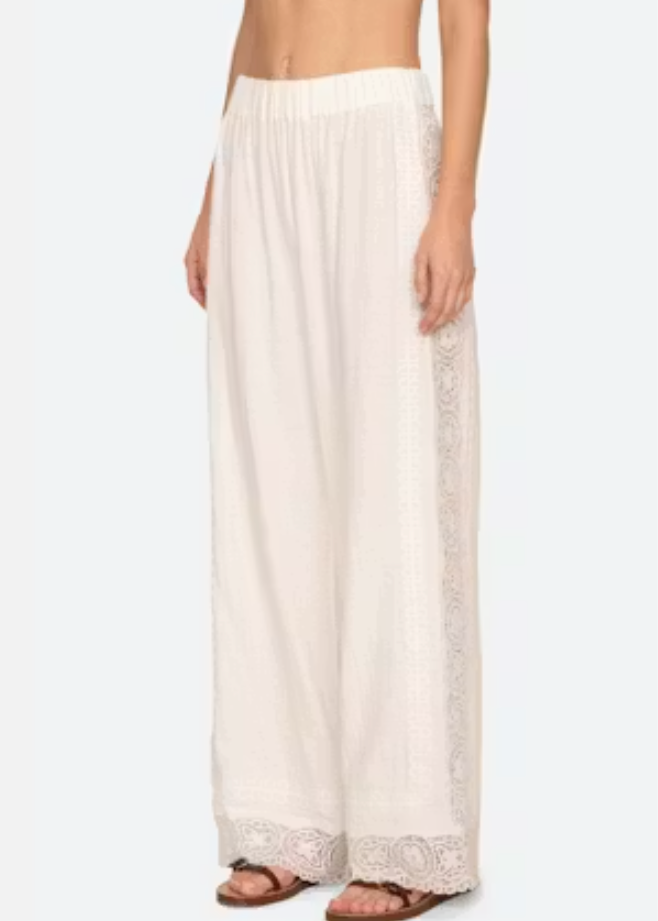 White lace-trimmed pants worn by a person on a white background