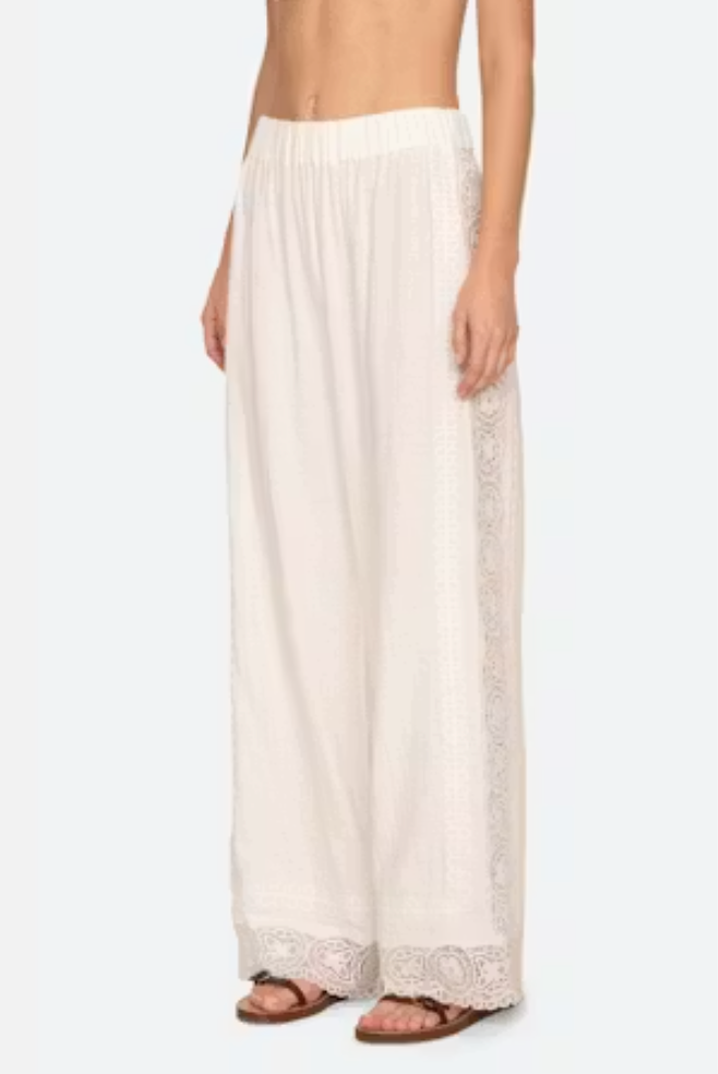 White lace-trimmed pants worn by a person on a white background