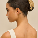 Woman with a stylish hair bun featuring a gold fish hair clip against a neutral background