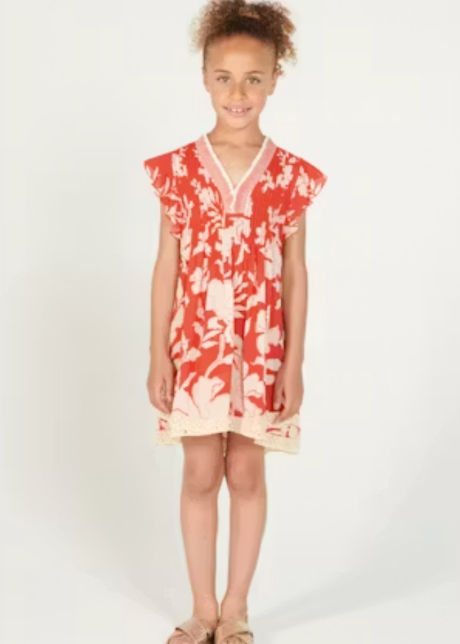 Young girl wearing a red and white floral dress on a white background