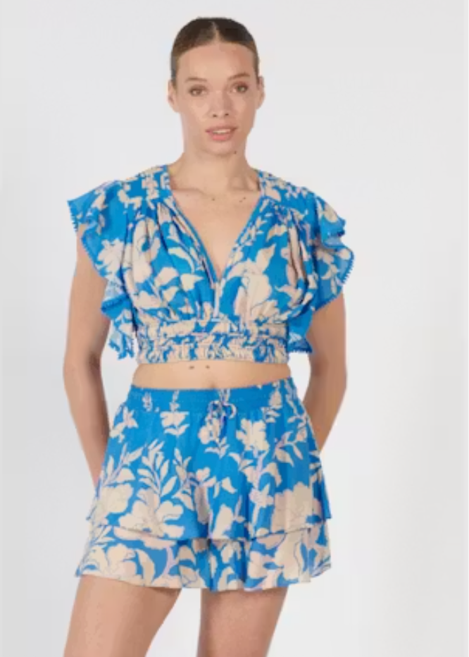 Woman wearing a blue floral two-piece outfit on a white background