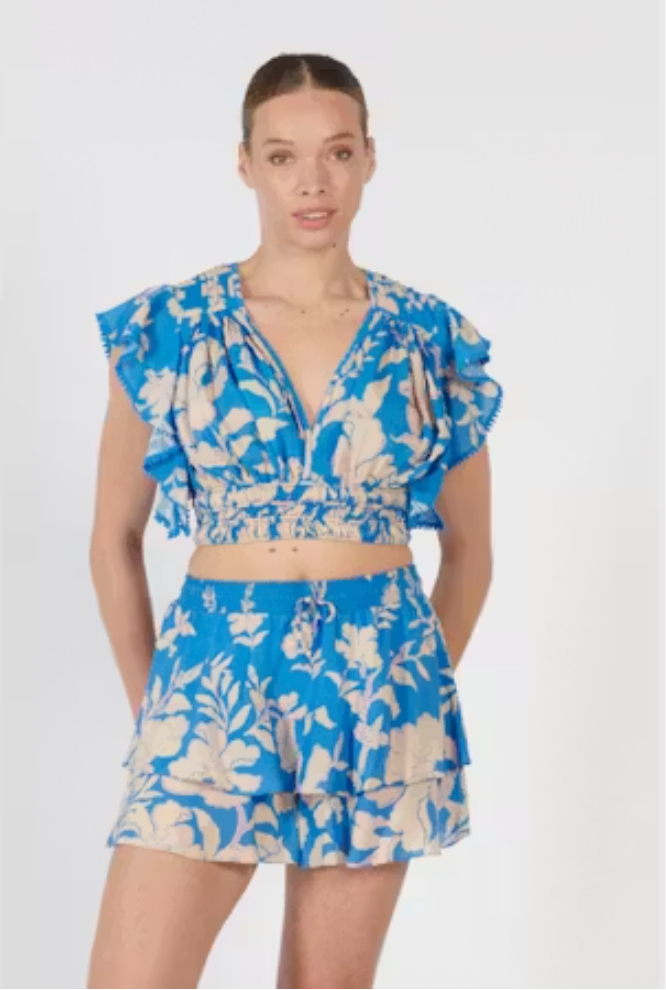 Woman wearing a blue floral two-piece outfit on a white background