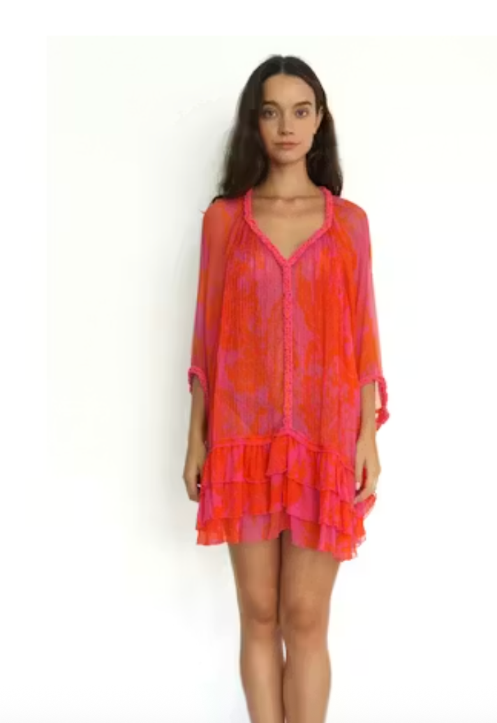 Woman wearing a vibrant orange and pink dress on a white background