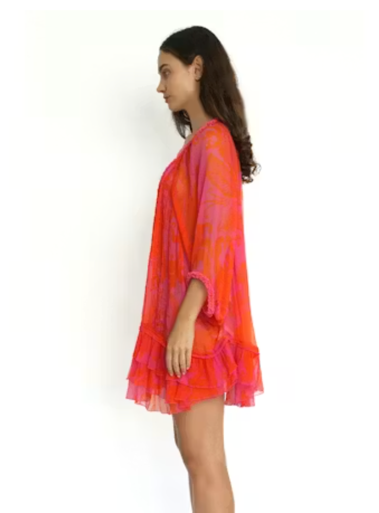 Woman wearing a vibrant orange and pink tie-dye dress on a white background