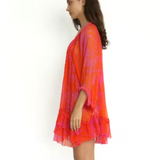 Woman wearing a vibrant orange and pink tie-dye dress on a white background
