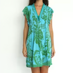 Woman wearing a turquoise and green patterned dress on a white background