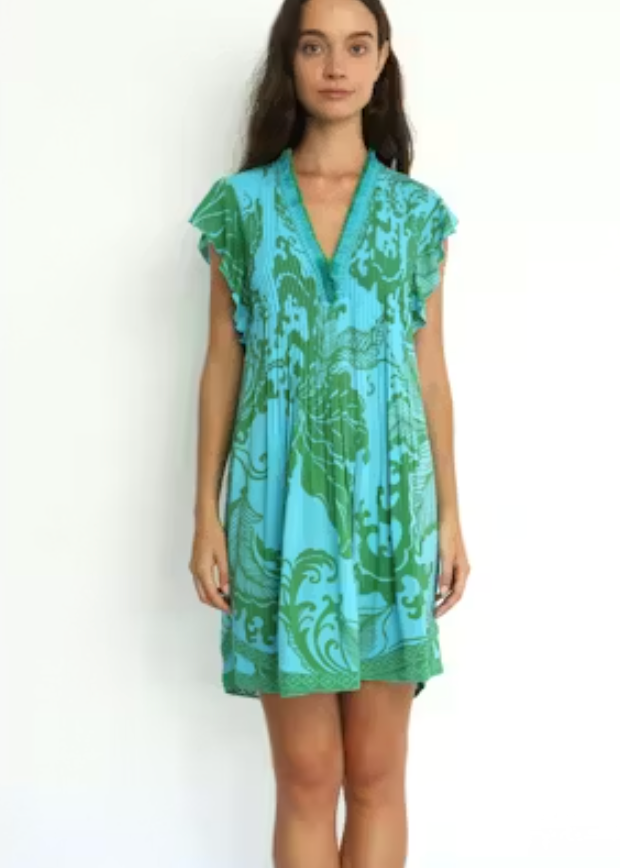 Woman wearing a turquoise and green patterned dress on a white background