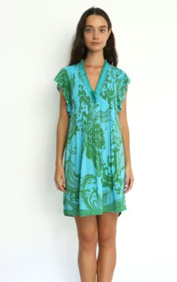 Woman wearing a turquoise and green patterned dress on a white background