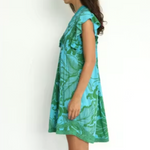 Woman wearing a green and blue patterned dress on a white background