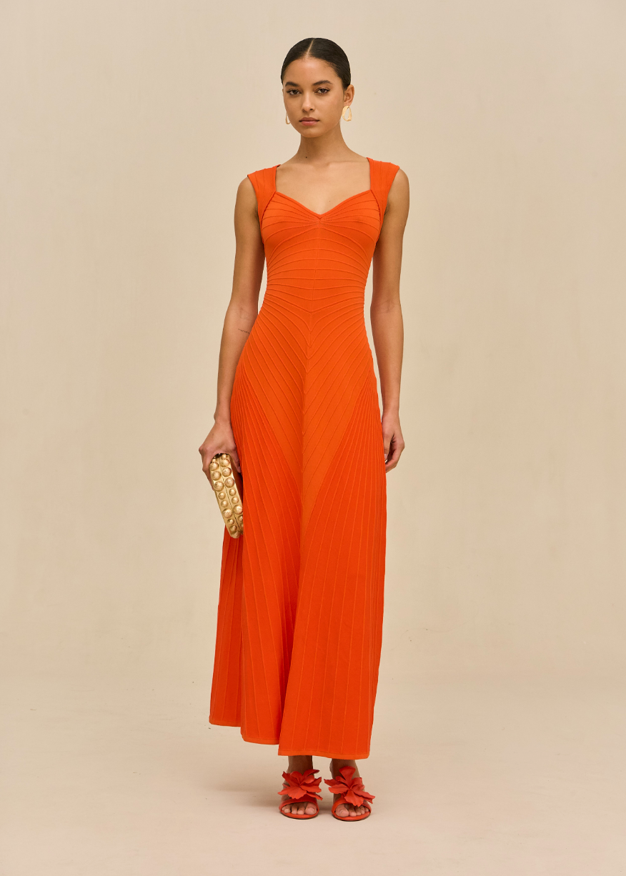 Woman wearing an orange dress against a beige background