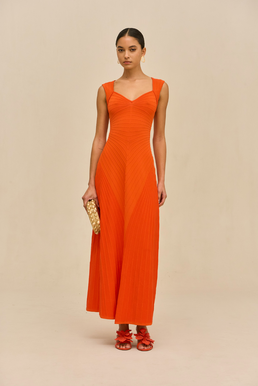 Woman wearing an orange dress against a beige background